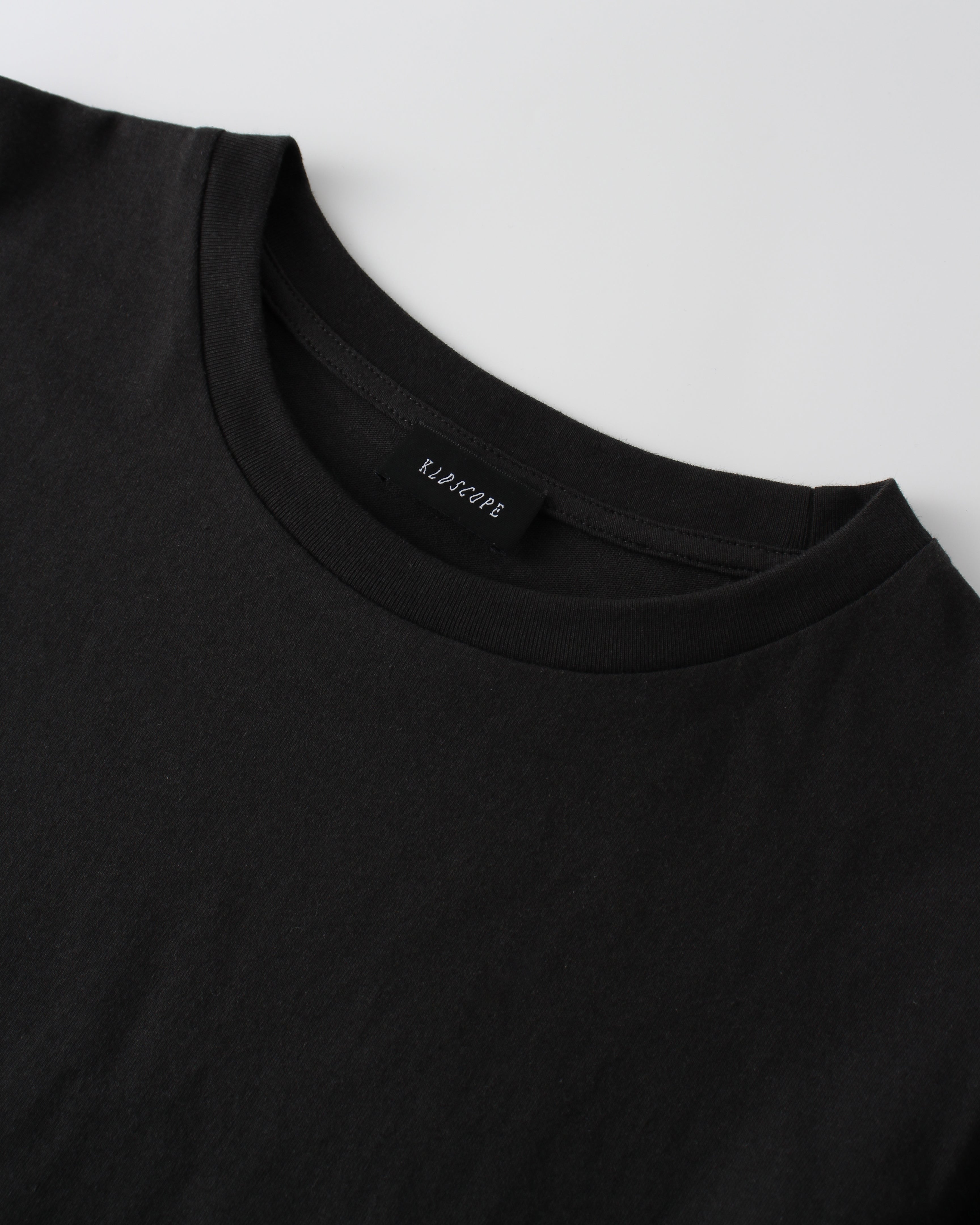 Black t-shirt with a brand "KLDSCOPE" label on a white background