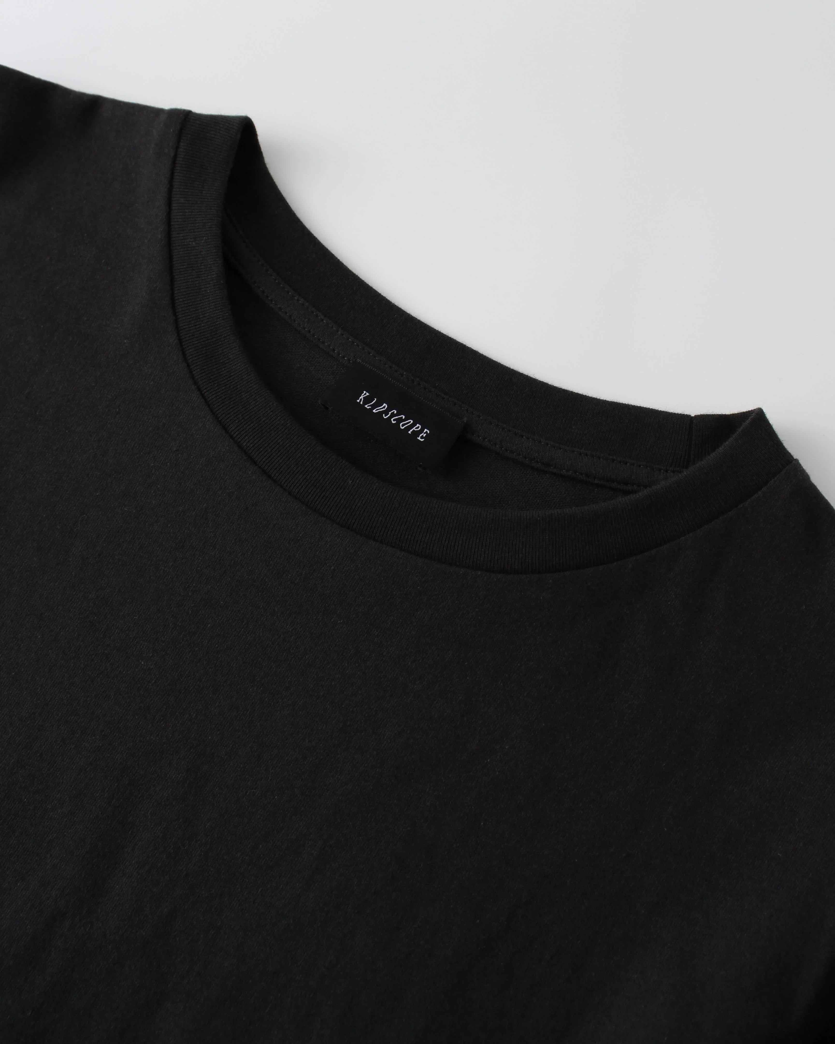 Black t-shirt with a brand "KLDSCOPE" label on a white background