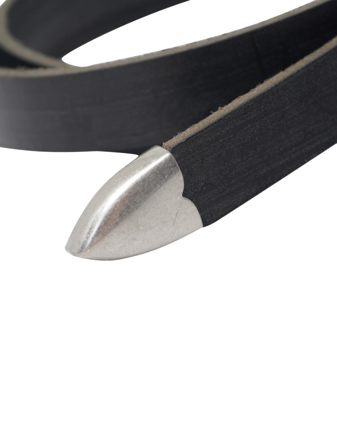 Image of a stylish black leather Western belt's metallic tips close up, placed on a white surface.