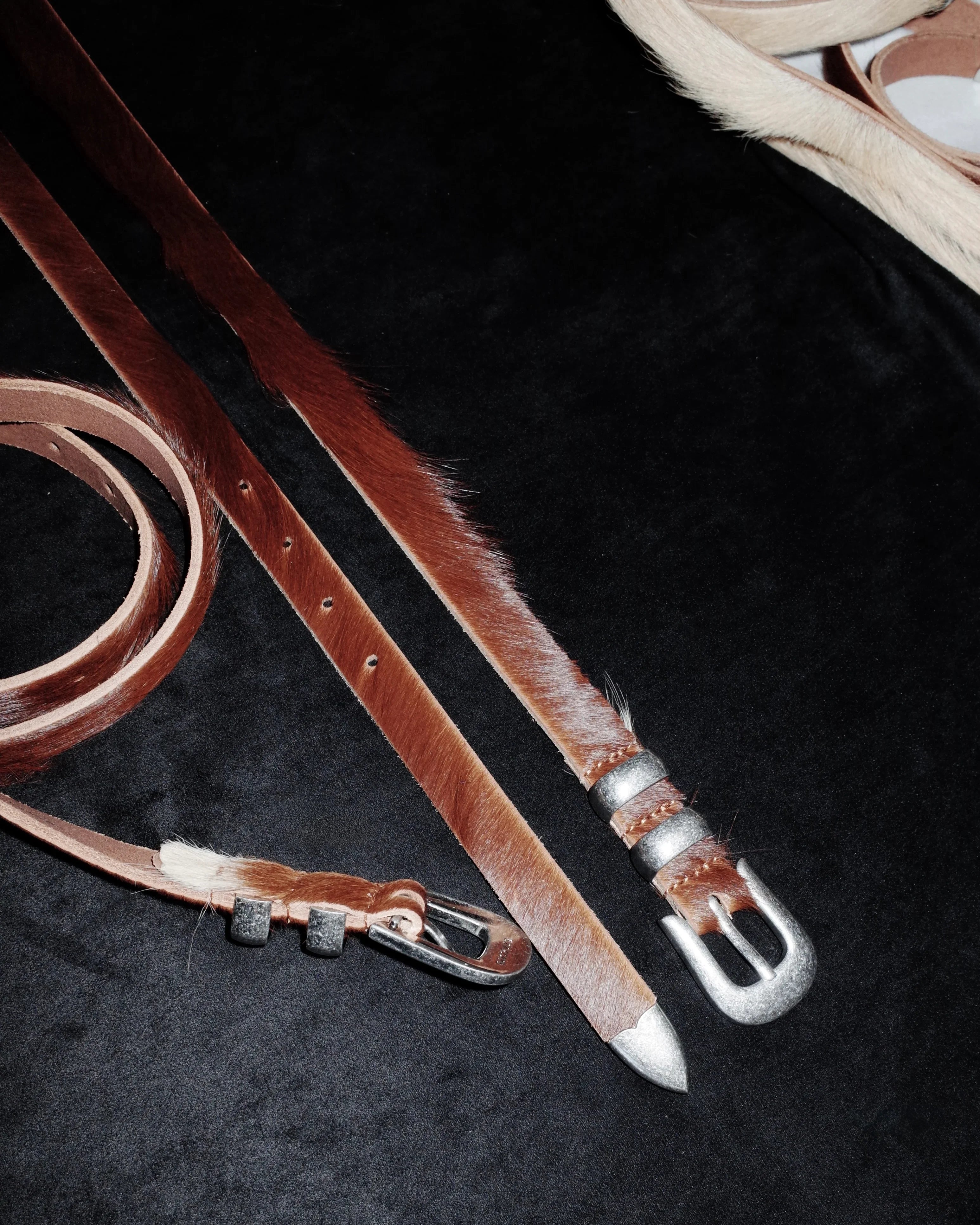 Brown leather Western belt strap with silver buckle on a dark surface