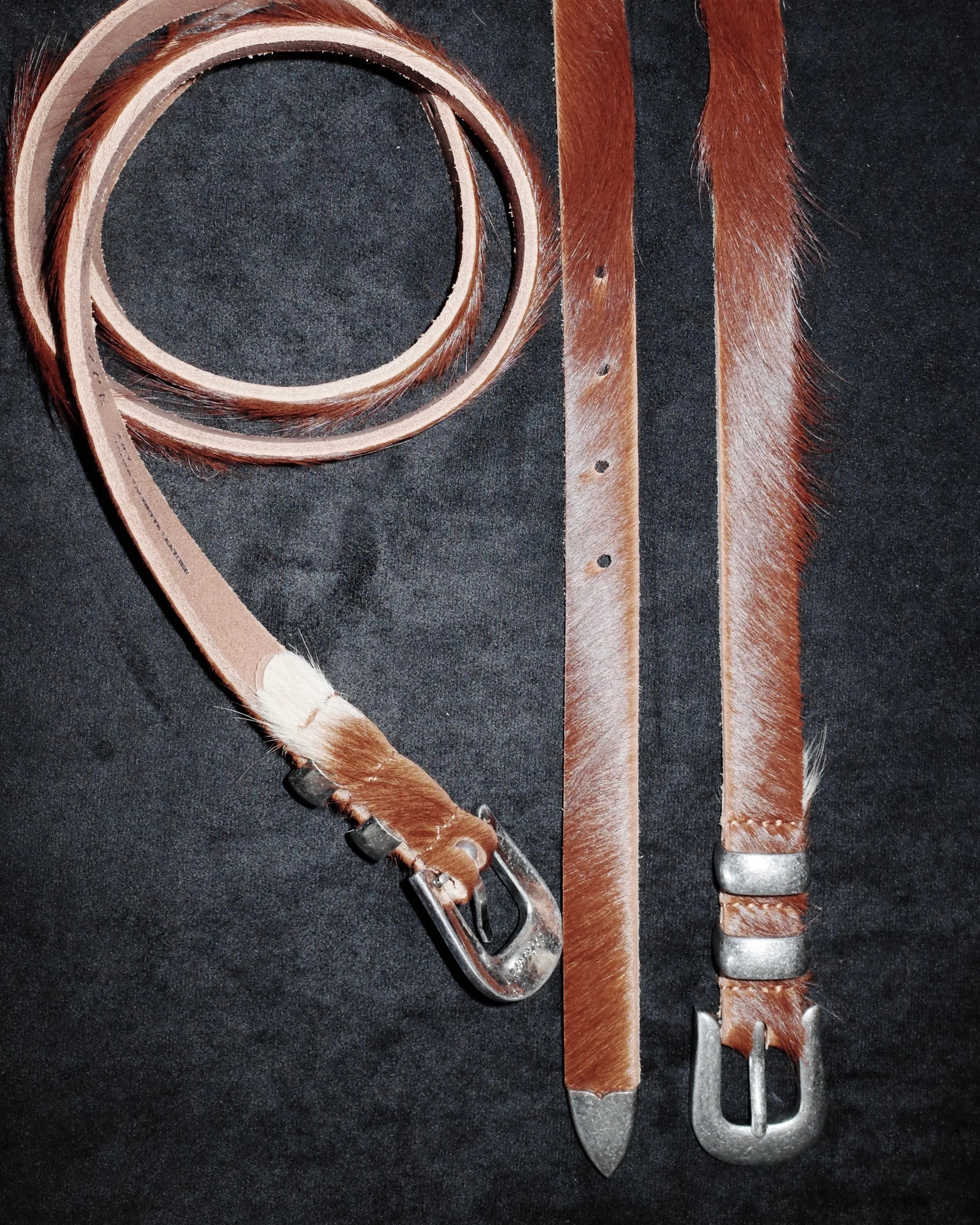 Brown leather Western belt with silver buckle on a dark background