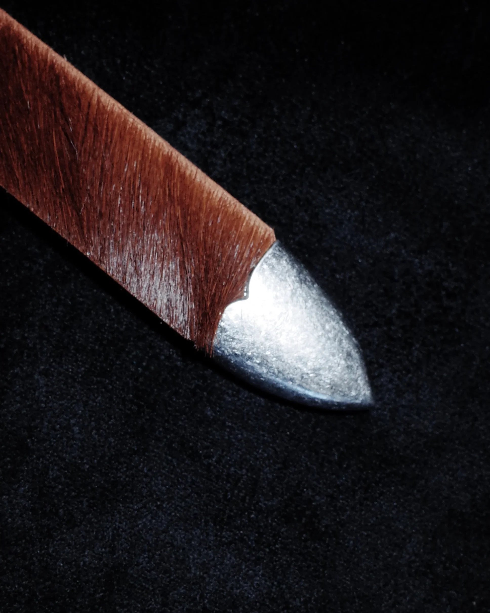 Leather western belt with metallic tip on a black background