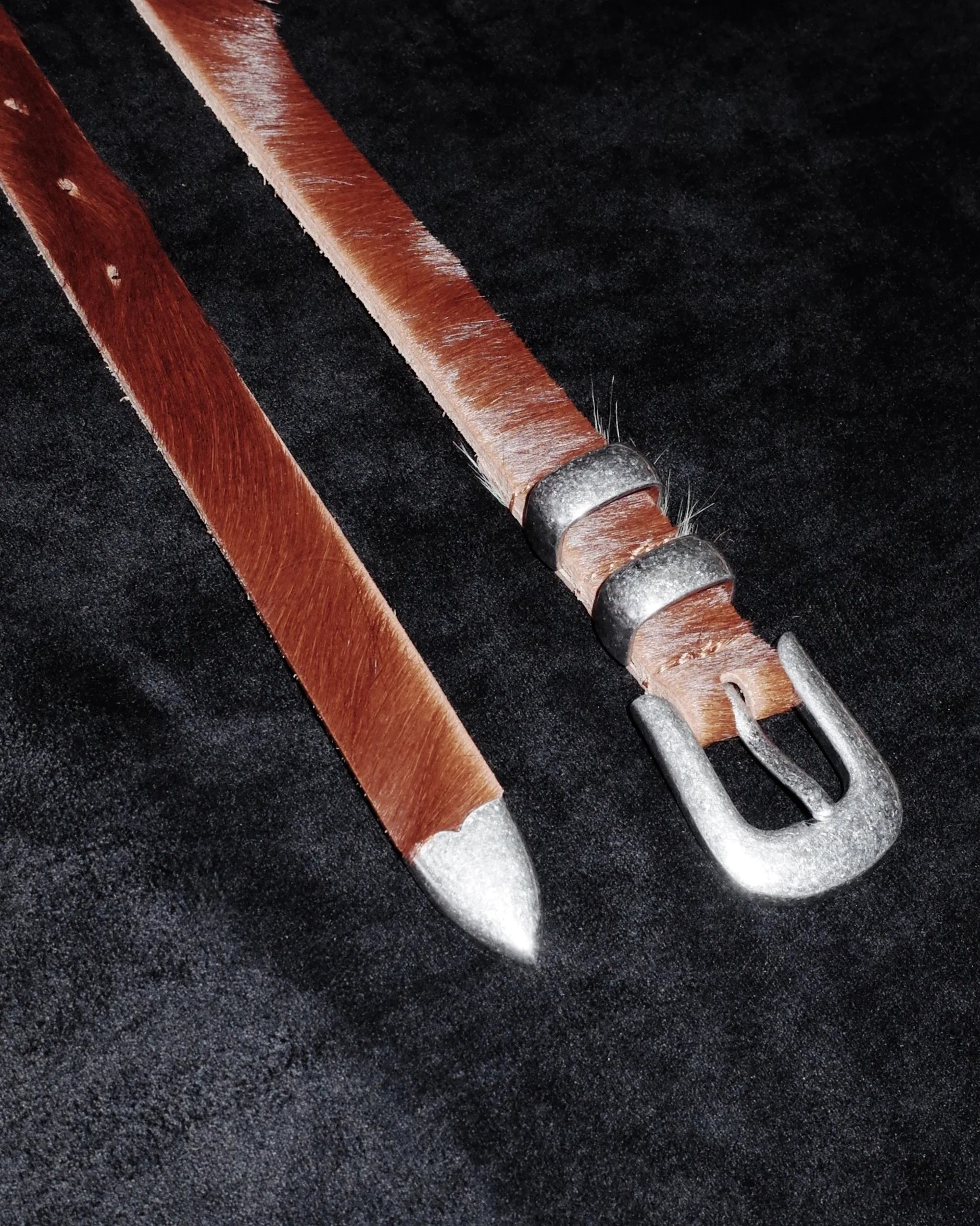 Brown leather Western belt with silver buckle on a dark textured background