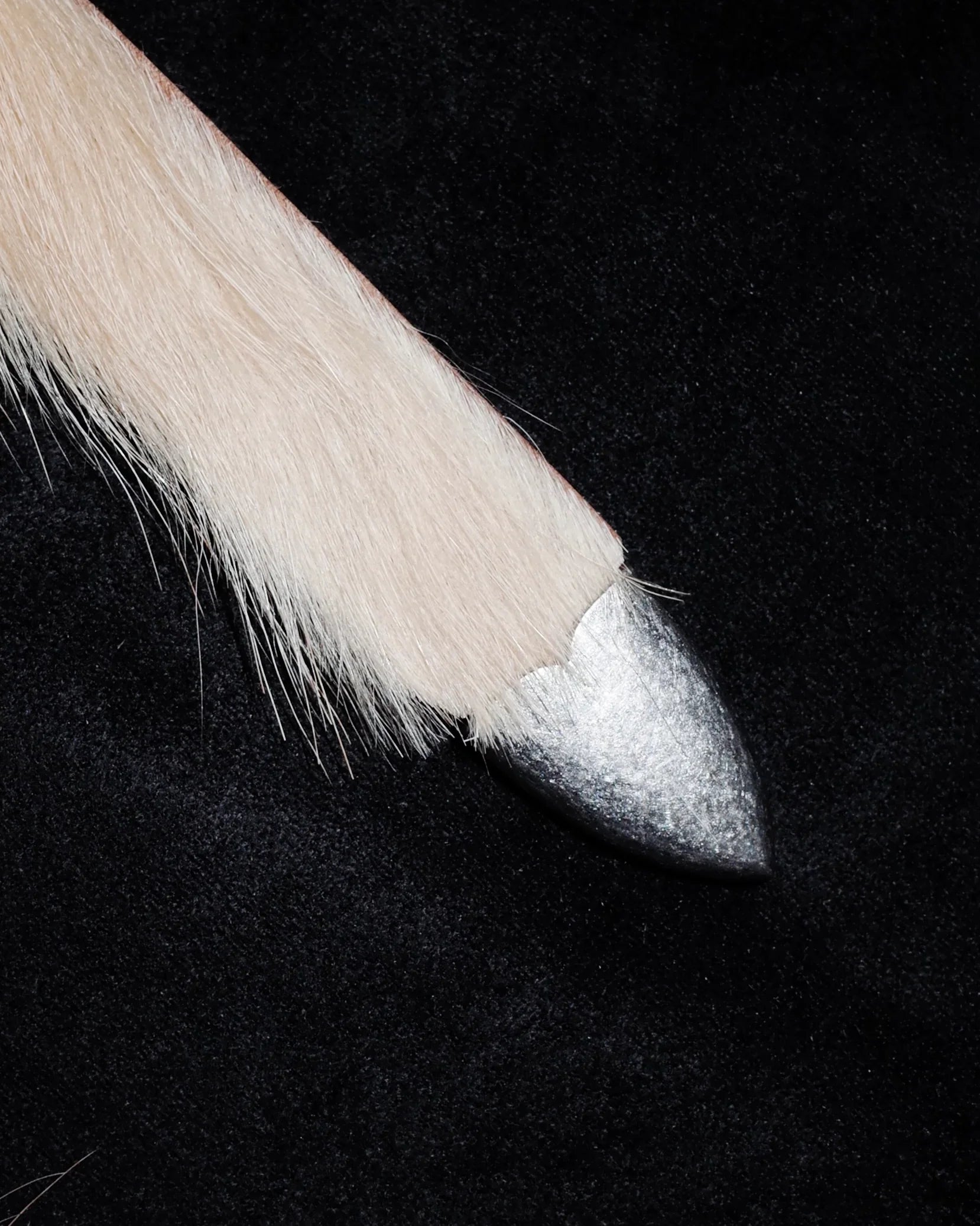 Close-up of a leather Western belt with a metal tip on a black background