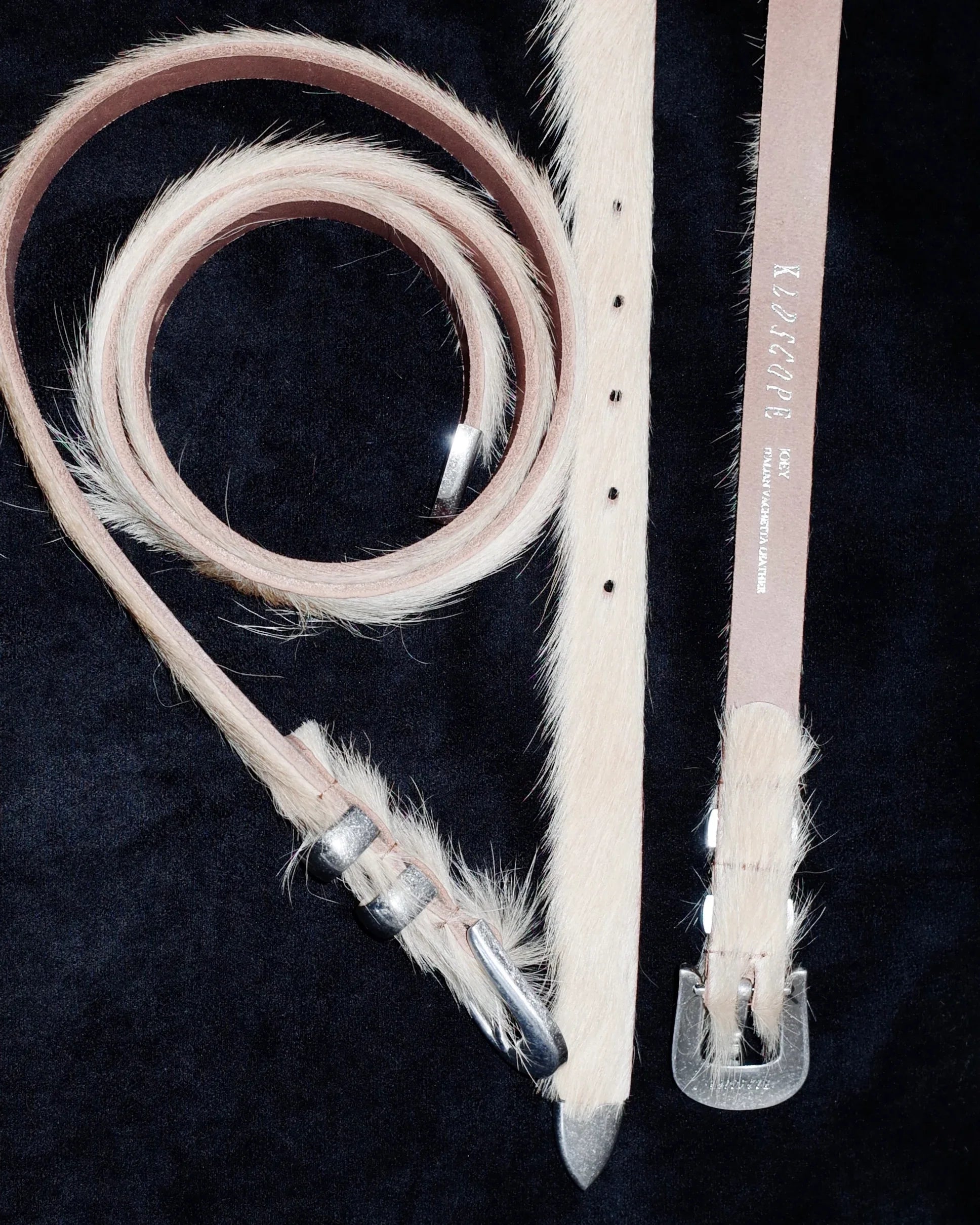 beige leather Western belt with metal buckles on a black background