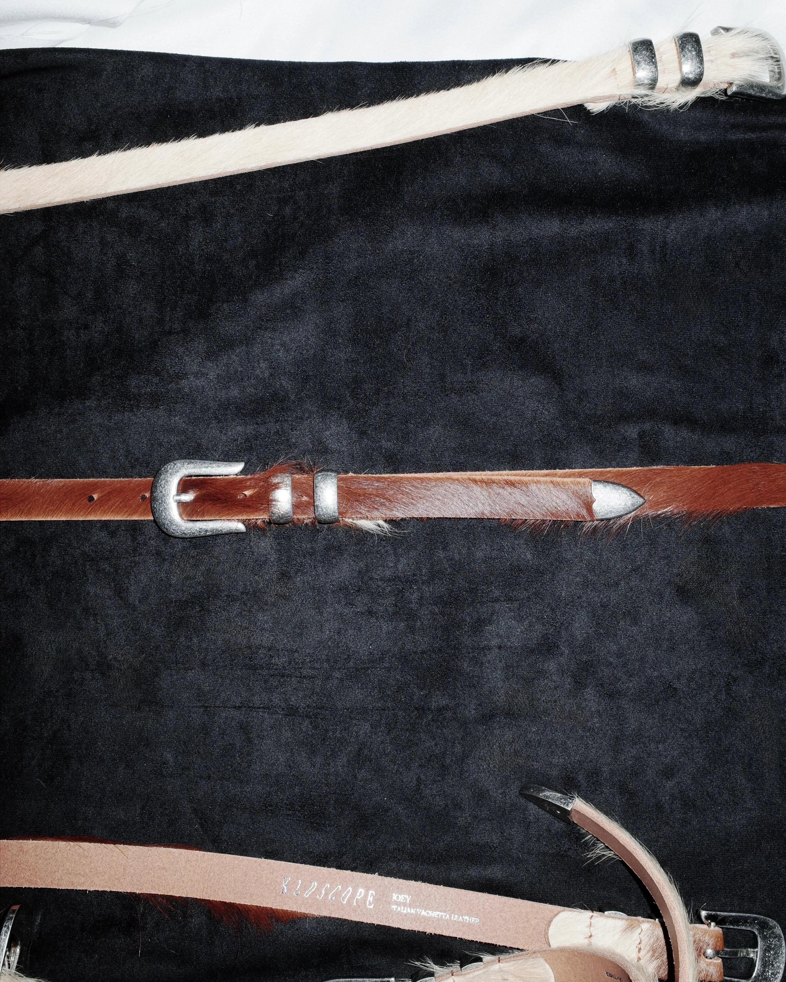 Set of leather Western belt straps with buckles on a dark textured surface