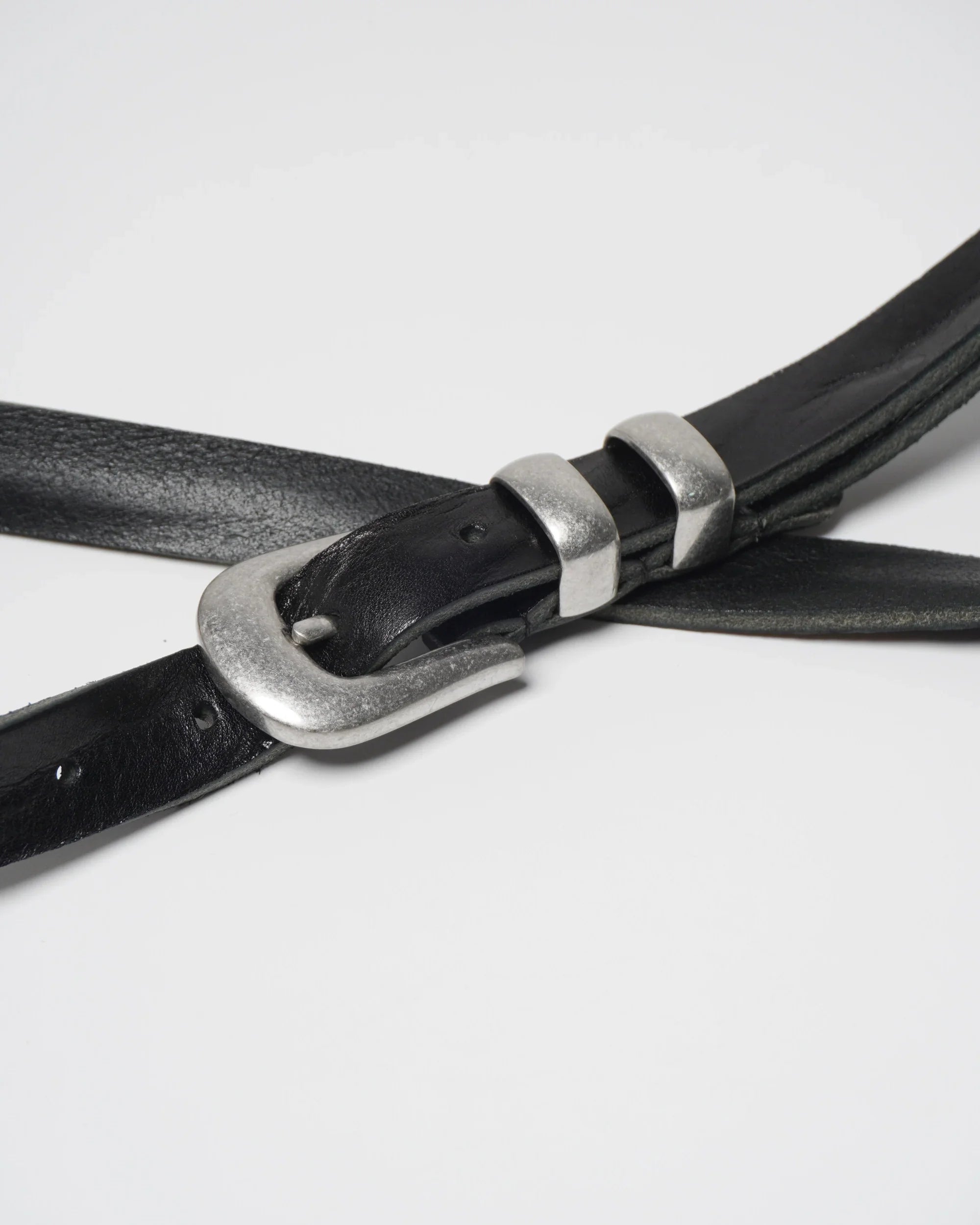 Image of a stylish black leather Western belt with metallic tips and buckles, placed on a white surface.