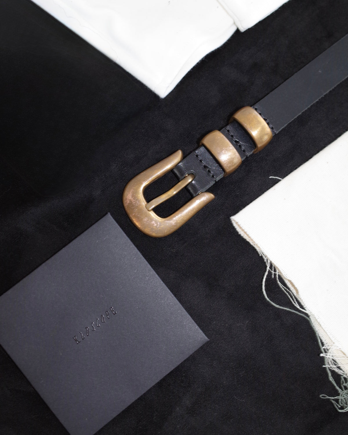 Unlacquered solid brass hardware on a black leather JOEY belt, showing natural tonal variation.