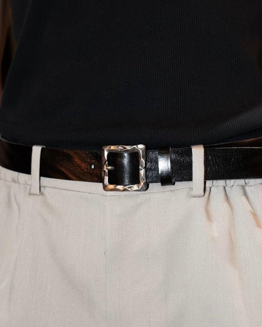 Square buckle belt pairing with black tank top and white trousers