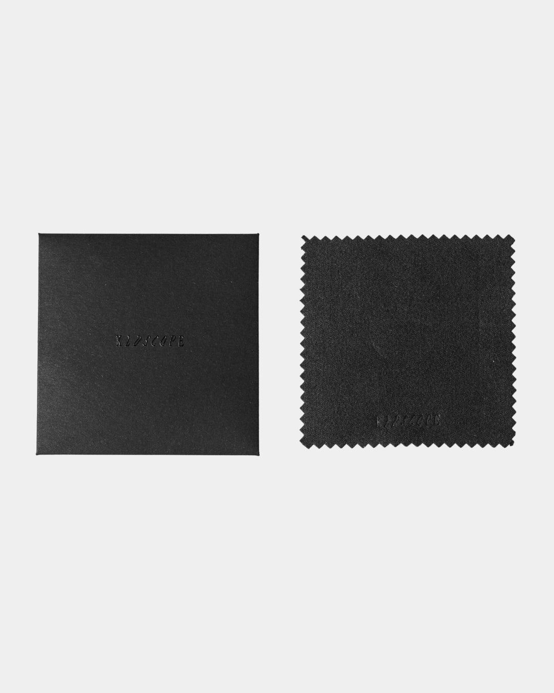 A black textured microfiber cleaning cloth with serrated edges next to its black textured square packaging box, both embossed with the brand name 'KLDSCOPE', on a light grey background.
