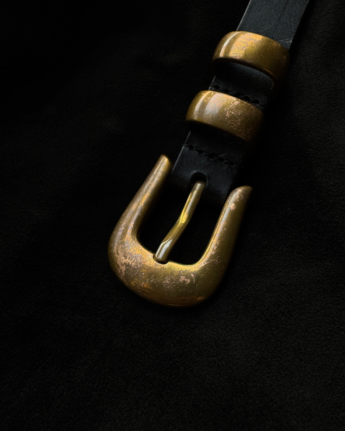 Close-up of naturally aged unlacquered solid brass buckle and two keepers on a black JOEY belt.