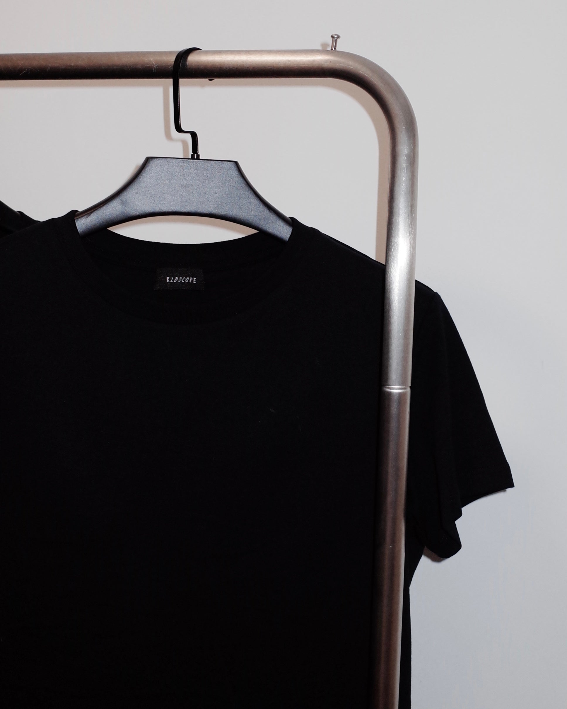 Black t-shirt on a hanger against a plain background