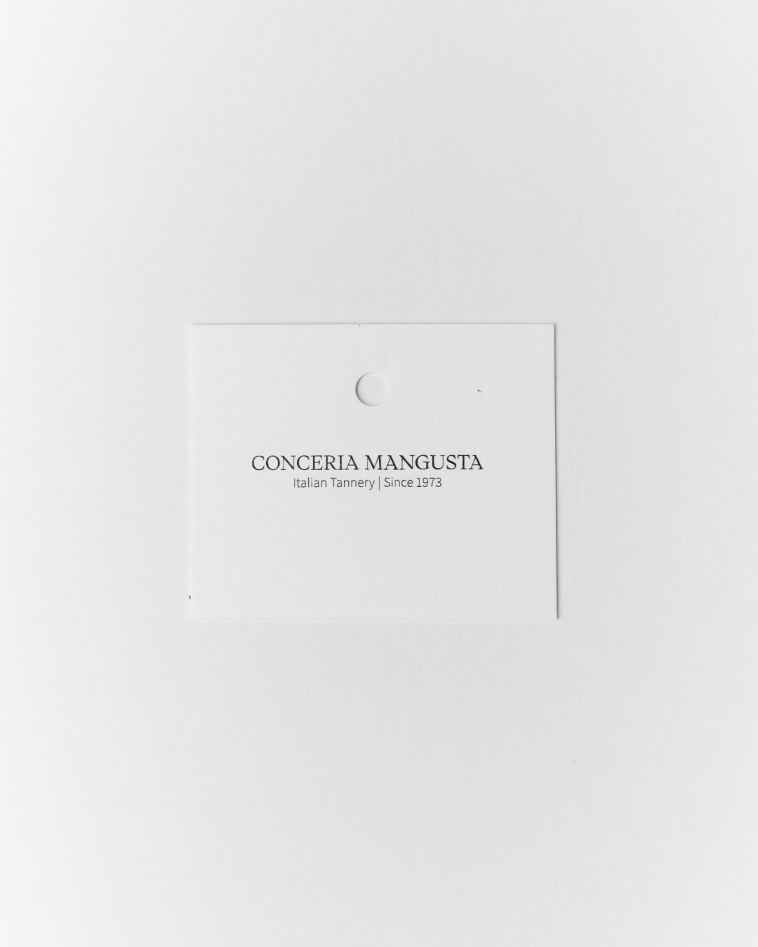 A minimalist white presentation card with the brand name 'CONCERIA MANGUSTA' and the tagline 'Italian Tannery | Since 1973' printed in black, centred on a solid white background.