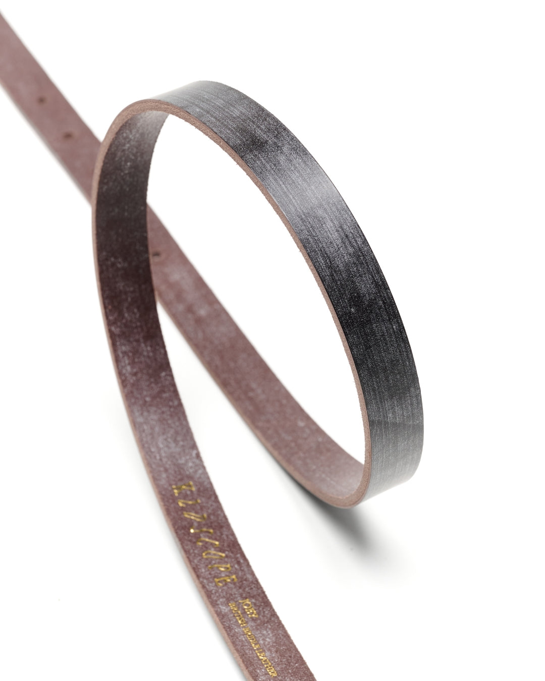 Curved strip of Choco Sedgwick bridle leather showing the slim 20mm profile and hand-finished edge of the JOEY belt.