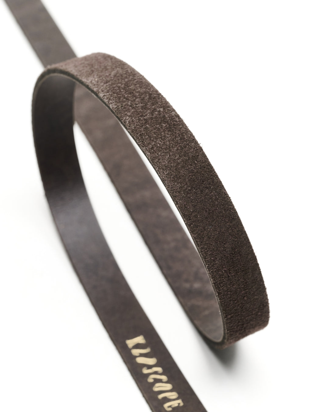A charcoal brown textured leather belt with the brand name 'KLDSCOPE' printed in gold script, shown on a clean white background.