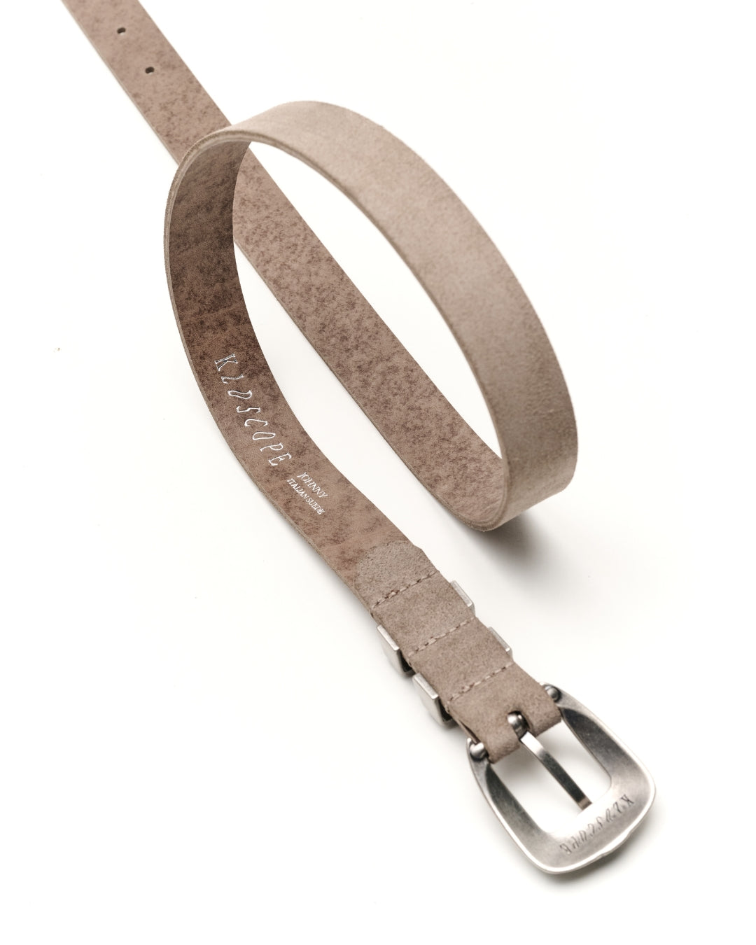 A sand-grey suede Western belt with a silver-tone metal buckle, shown on a clean white background. The brand name 'KLDSCOPE' is visible, printed on the inner strap and engraved on the buckle.