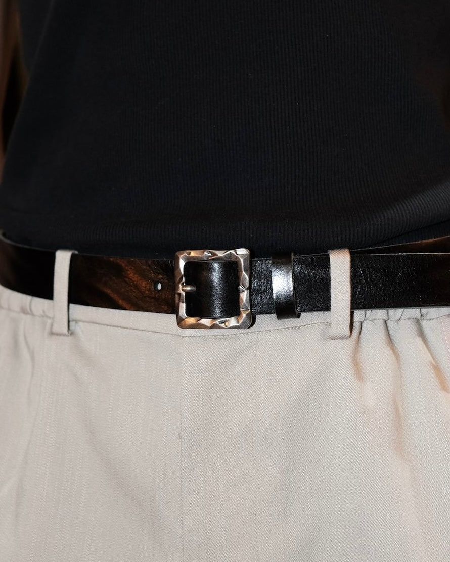 Square buckle belt pairing with black tank top and white trousers